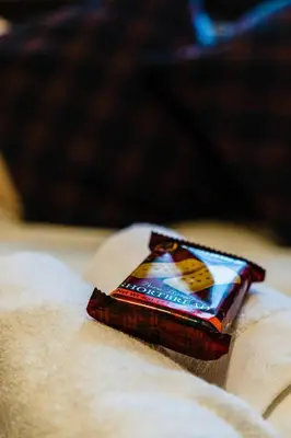 a packet of candy sitting on top of a bed at Cheerful 1 Bedroom Homely Apartment, Sleeps 4 Guest Comfy, 1 x Double Bed, 1 x Sofa Bed, Parking, Free WiFi, Suitable For Business, Leisure Guest,Glasgow, Glasgow West End, Near City Centre, Perfect for Common Wealth Games 2026 in Glasgow