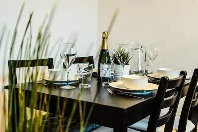 a black table with a bottle of wine and glasses at Cheerful 1 Bedroom Homely Apartment, Sleeps 4 Guest Comfy, 1 x Double Bed, 1 x Sofa Bed, Parking, Free WiFi, Suitable For Business, Leisure Guest,Glasgow, Glasgow West End, Near City Centre, Perfect for Common Wealth Games 2026 in Glasgow