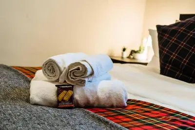 a pile of towels sitting on top of a bed at Cheerful 1 Bedroom Homely Apartment, Sleeps 4 Guest Comfy, 1 x Double Bed, 1 x Sofa Bed, Parking, Free WiFi, Suitable For Business, Leisure Guest,Glasgow, Glasgow West End, Near City Centre, Perfect for Common Wealth Games 2026 in Glasgow