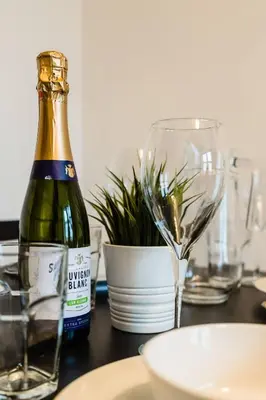 a bottle of champagne sitting on a table with a plant at Cheerful 1 Bedroom Homely Apartment, Sleeps 4 Guest Comfy, 1 x Double Bed, 1 x Sofa Bed, Parking, Free WiFi, Suitable For Business, Leisure Guest,Glasgow, Glasgow West End, Near City Centre, Perfect for Common Wealth Games 2026 in Glasgow