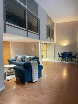 a living room with a blue couch and a dining room at SEC Hydro Duplex in Finnieston in Glasgow