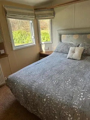 a bedroom with a bed with a blue comforter and two windows at Aspen Scenic 53 in Ardentinny