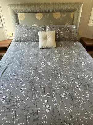 a bed with a gray comforter with a pillow on it at Aspen Scenic 53 in Ardentinny