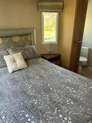 a bed with a blue comforter with a pillow on it at Aspen Scenic 53 in Ardentinny