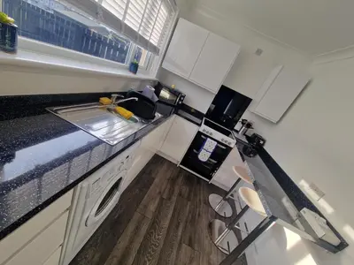 a small kitchen with white cabinets and a counter top at Cozy Shotts House with 2 Bedrooms in Kirk of Shotts
