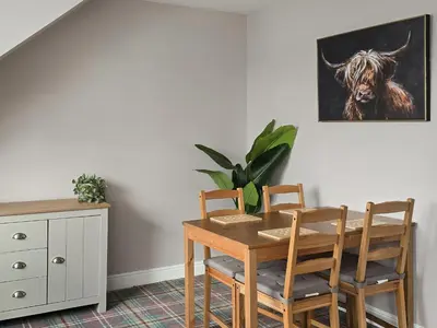 a dining room table and chairs with a picture of a cow at Holy Loch View in Strone