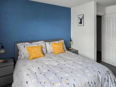 a bedroom with a bed with blue walls and yellow pillows at Holy Loch View in Strone