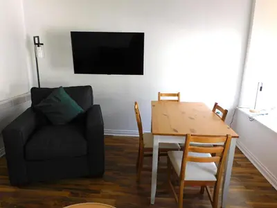 a living room with a table and a chair and a television at No 1 - 2 bedroom apartment in Lanark Town Centre in Lanark