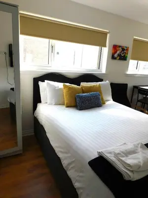 a bedroom with a large white bed with yellow pillows at No 3 - Modern Studio Apartment in Lanark Town Centre in Lanark