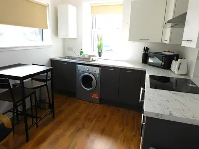 a kitchen with a washing machine in the middle at No 3 - Modern Studio Apartment in Lanark Town Centre in Lanark