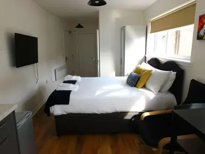 a bedroom with a bed with white sheets and yellow pillows at No 3 - Modern Studio Apartment in Lanark Town Centre in Lanark