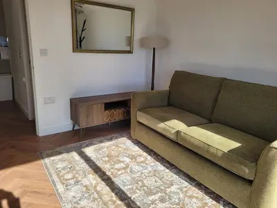 a living room with a couch and a mirror at Hot Tub Cottage in Ayrshire in Stewarton