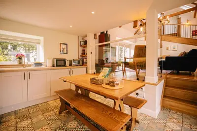 a kitchen with a wooden table and a dining room at Stunning Barn Conversion in Dunlop
