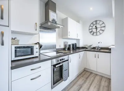 a kitchen with white cabinets and a clock on the wall at En-suite - Glasgow Riverside in Glasgow