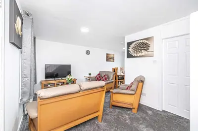 a living room with two chairs and a television at Pure Home Oakley Park View by TBA in Dunfermline