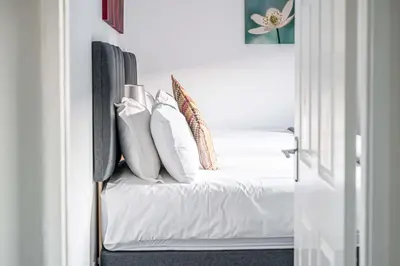 a room with a white couch with pillows at Pure Home Oakley Park View by TBA in Dunfermline
