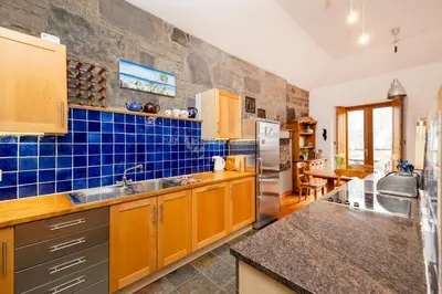 a kitchen with wooden cabinets and a blue tiled wall at Edinburgh New Town Deluxe Apartment with Terrace in Edinburgh