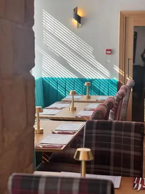 a row of long tables in a room with plaid chairs at The Cornhill Inn in Falkirk