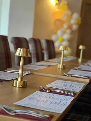 a long wooden table with napkins and lamps on it at The Cornhill Inn in Falkirk