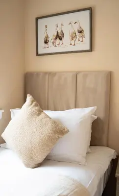 a bed with white pillows and a picture on the wall at Marina House in Bathgate
