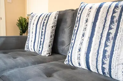 a gray couch with two pillows on it at Marina House in Bathgate