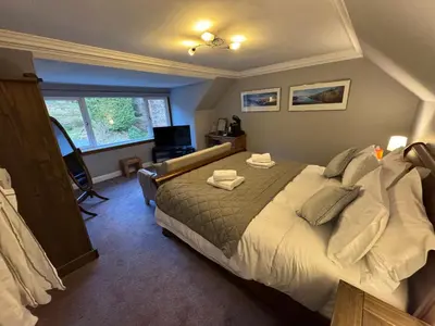 a bedroom with a large bed and a window at Crannaig House in Aberfoyle