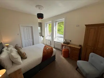 a bedroom with a bed and a chair and a window at Glenroy Guest House in Oban