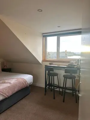 a bedroom with a bed and a desk and a window at Glenroy Guest House in Oban