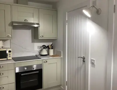 a kitchen with white cabinets and a stove top oven at Cottage in Mid Calder Village near Edinburgh in Mid Calder