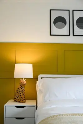 a bed with a yellow headboard and a lamp on a night stand at Homely 2 Bed House with Private double driveway in Oban