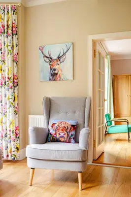 a living room with a chair and a painting of a deer at Amulree, Edinburgh City in EDI