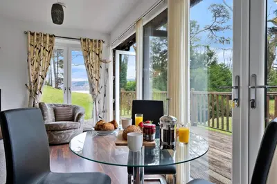 a dining room with a glass table and a balcony at Finest Retreats - The Turbine House in Achahoish