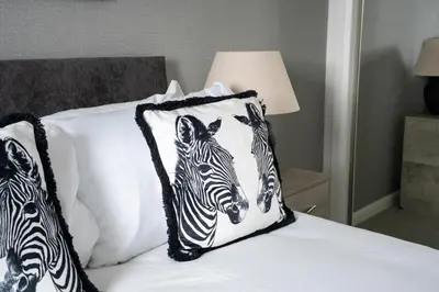 a bed with three zebra pillows on it at Stirling Street Stays in Tillicoultry