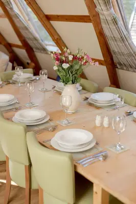 a wooden table with plates and glasses and flowers on it at Villa Rabbie Burns Lodge by Interhome in Straiton