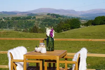 a table with a vase of flowers and two chairs at The Barn, Summerhill Farm Stays in Balmaclellan