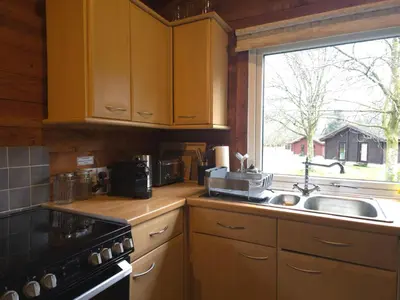 a kitchen with wooden cabinets and a sink and a window at Stravaigin Lodges in Rashfield