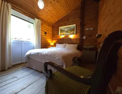 a bedroom with a bed in a wooden room at Stravaigin Lodges in Rashfield