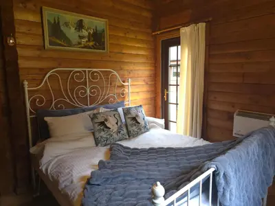 a bed in a room with a wooden wall at Stravaigin Lodges in Rashfield