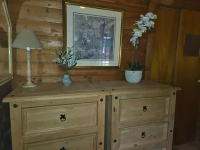 a wooden dresser with a lamp and flowers on it at Stravaigin Lodges in Rashfield