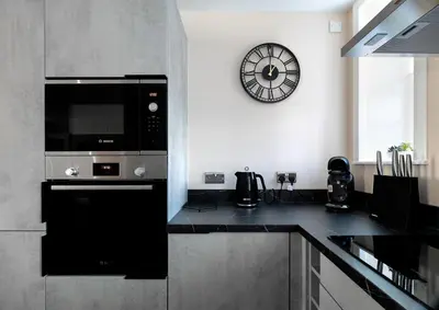 a kitchen with a microwave and a clock on the wall at Castle Street Apartments - Luxury Scalpsie Apartment in Rothesay