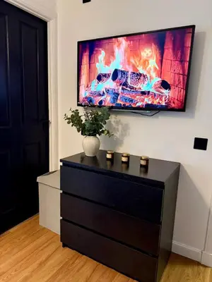 a dresser with a tv on a wall at 2 Bedroom Apartment near Glasgow City Centre, Celtic Park and Emirates Arena in Glasgow