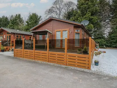 a large wooden cabin with a wooden fence at Lodge 2 in Auchterarder