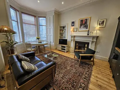 a living room with a leather couch and a fireplace at Comely Bank Coorie in Edinburgh