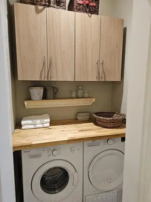 a kitchen with a washing machine and wooden cabinets at Comely Bank Coorie in Edinburgh