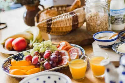 a table topped with plates of fruit and glasses of orange juice at B&B on Beautiful Organic Homestead, Edinburgh in Loanhead