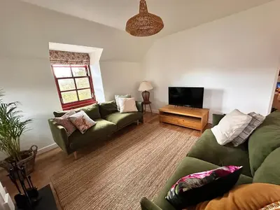 a living room with a green couch and a television at Drymen View in Drymen