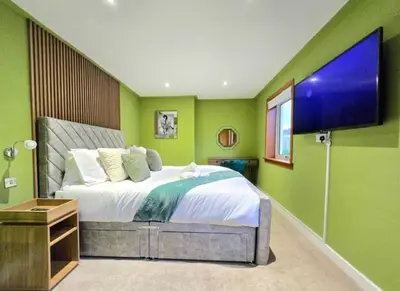 a bedroom with a large bed with green walls at Super luxury 2 bedroom, full house sleep 5 with garden & parking close to airport in Elderslie