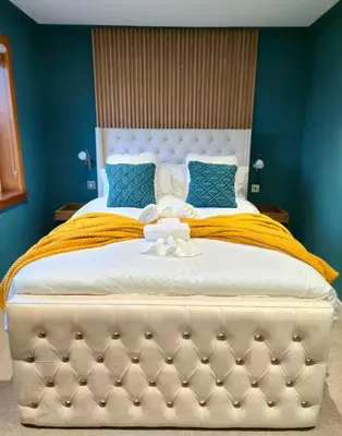 a bedroom with a large bed with blue walls at Super luxury 2 bedroom, full house sleep 5 with garden & parking close to airport in Elderslie