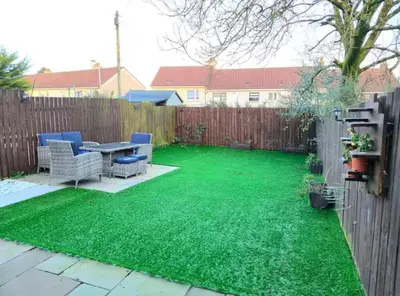 a backyard with green grass and a wooden fence at Super luxury 2 bedroom, full house sleep 5 with garden & parking close to airport in Elderslie