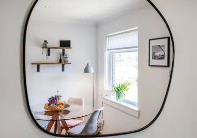 a mirror in a white room with a table and chairs at Cairn BNB Introduces Mavisbank Gardens - where homely charm meets modern living in Glasgow